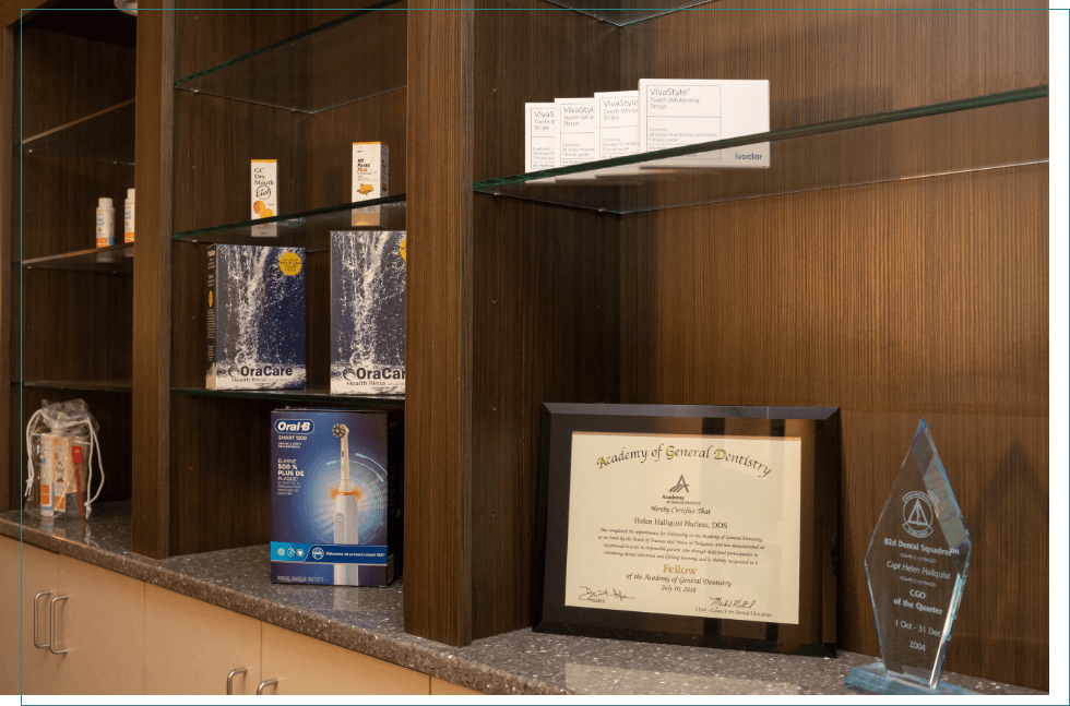 Shelf with framed dental degree awards and various oral hygiene products