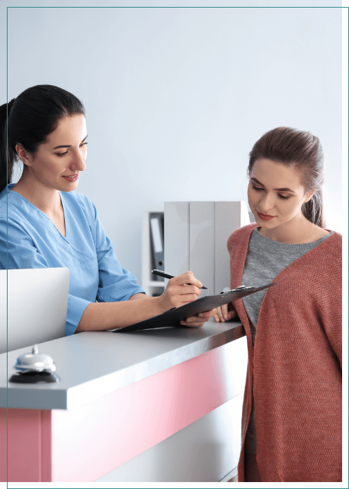 Dental office receptionist showing a clipboard to a patient