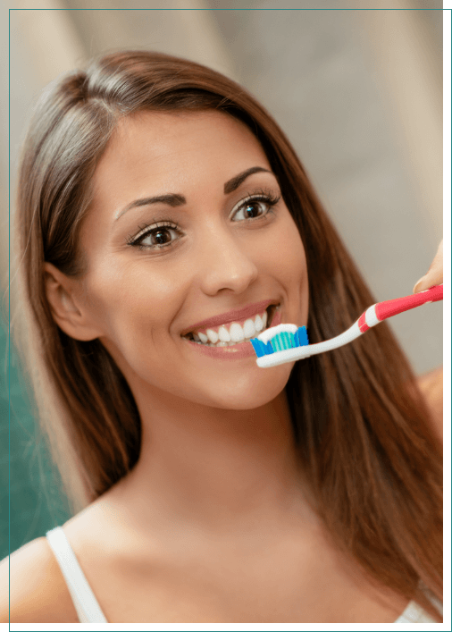 Woman smiling while brushing her teeth