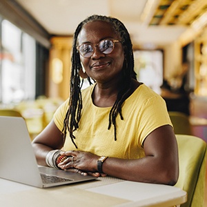 Woman smiling while working on laptop in restaurant