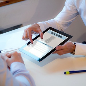 dentist showing a tablet with dental insurance on it