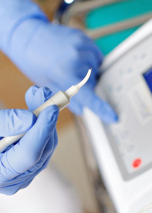 Gloved hands setting up soft tissue dental laser