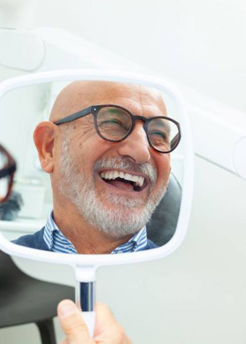 Face of happy dental patient reflected in mirror