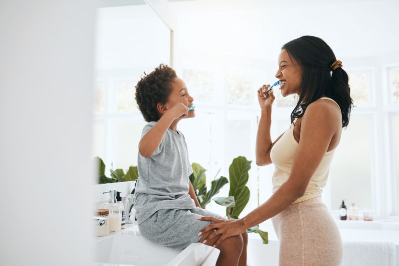 Mother and son brushing teeth together.