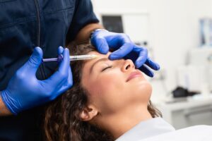 Gloved hands injecting Botox into woman's brow area
